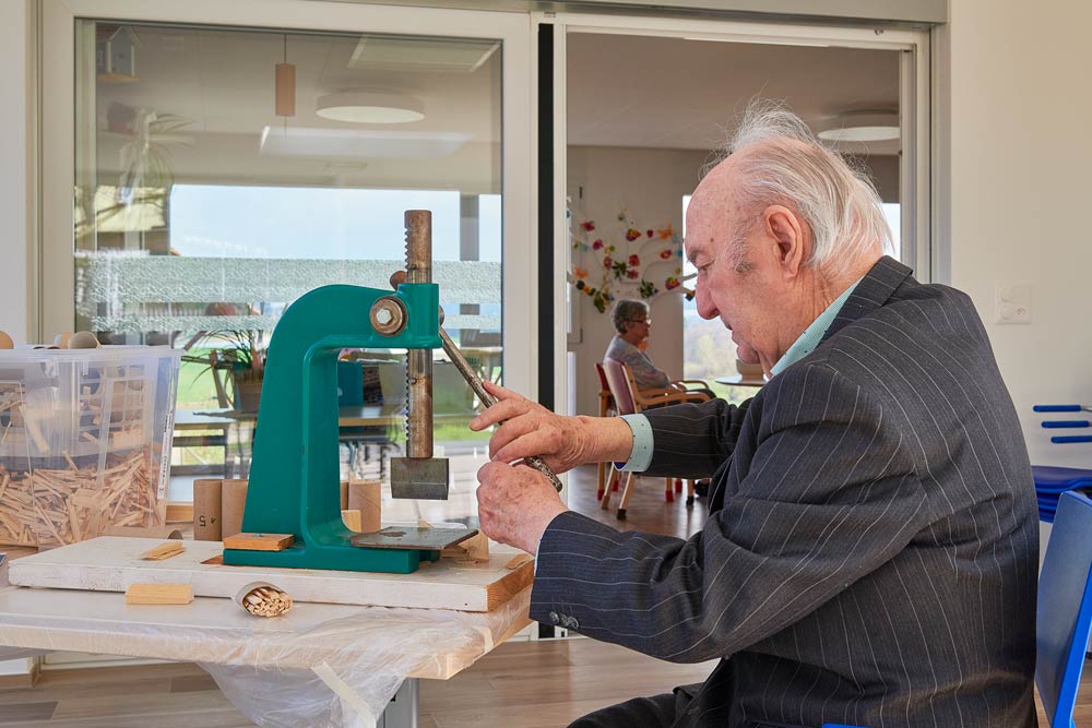 Ein Mann im Altersheim arbeitet an einer Handwerksmaschine