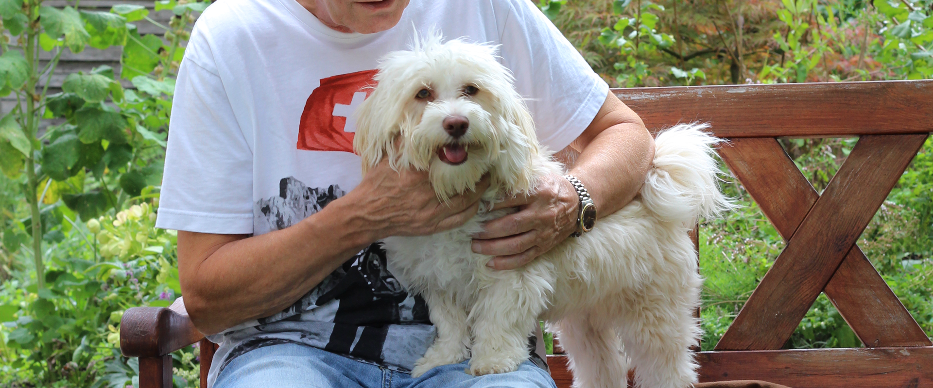 Mensch mit weissem Hund auf Bank