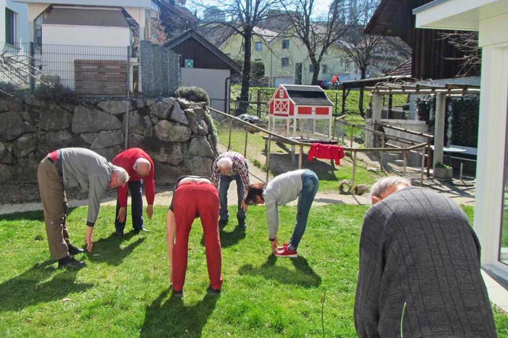 Ältere Menschen beim gemeinsamen Yoga auf dem Rasen des Haus Herbschtzytlos