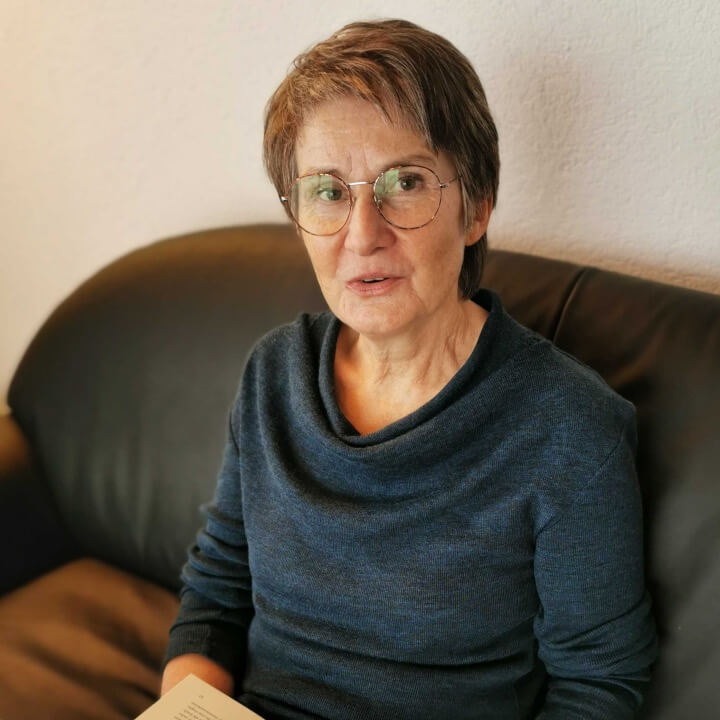Susanne Senn sitzt auf ihrem Sofa mit einem Buch